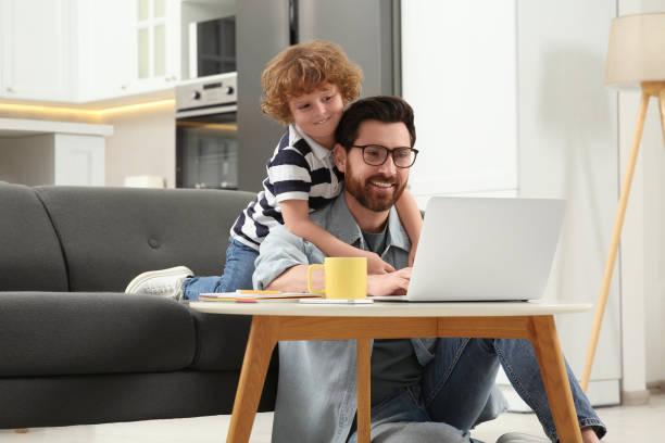 istock Man with laptop working remotely at home. Father and son at desk 1769756490