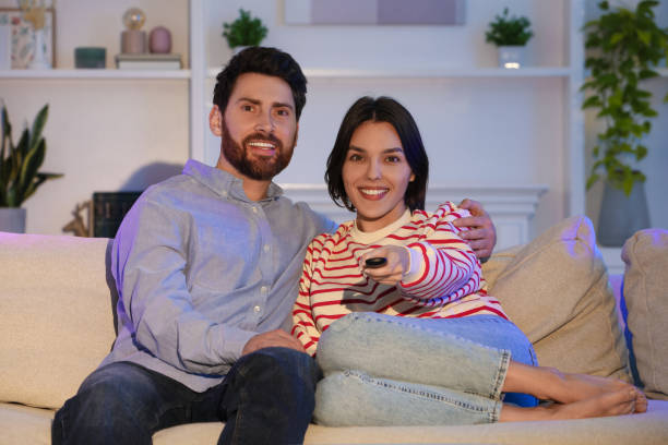 istock Happy couple watching TV on sofa at home 1769757055