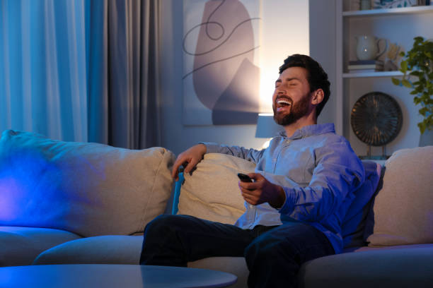 istock Laughing man watching TV on sofa at home, space for text 1769757061