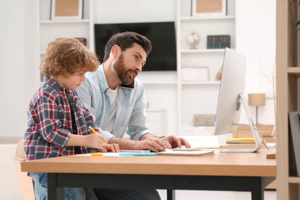 istock Man working remotely at home. Busy father talking on smartphone while his son drawing at desk 1769757584