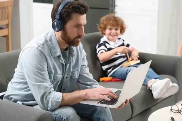 istock Father working remotely on laptop while his son playing with toys at home 1769757730