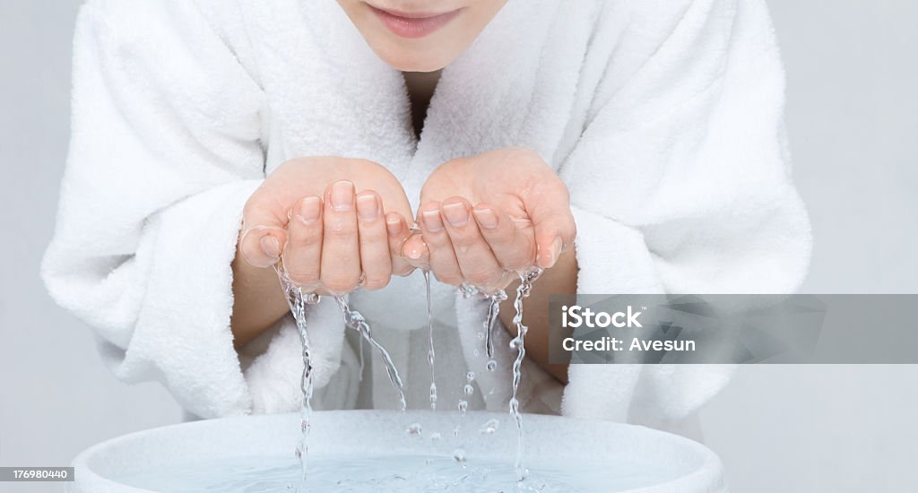 Woman splashing her face with water Young woman in white bathrobe washing face Washing Face Stock Photo