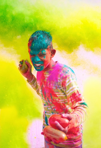 Young Indian boy playing with water balloons on Holi festival.