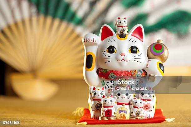 Waving Lucky Japanese Cat With A Fan In The Background Stock Photo - Download Image Now