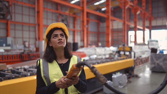 Female warehouse worker in charge of using a crane to raise rolls of metal sheets in the warehouse. to import metal sheet manufacturing belts