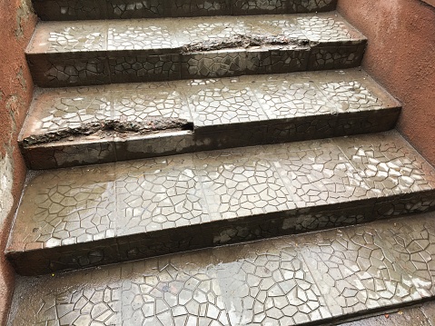 Broken sidewalk steps in rainy weather. Wet paving slabs. Close up