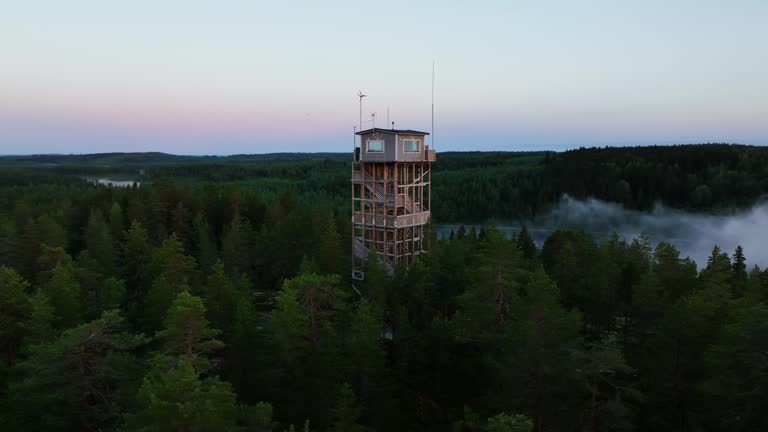 Aerial view orbiting the Haahninmaen nakotorni tower, misty morning in Finland