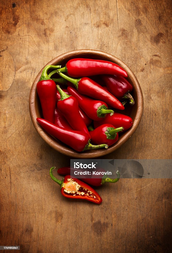 Red chili peppers in wooden bowl on wooden table Red Hot Chili Peppers in bowl over wooden background Bowl Stock Photo