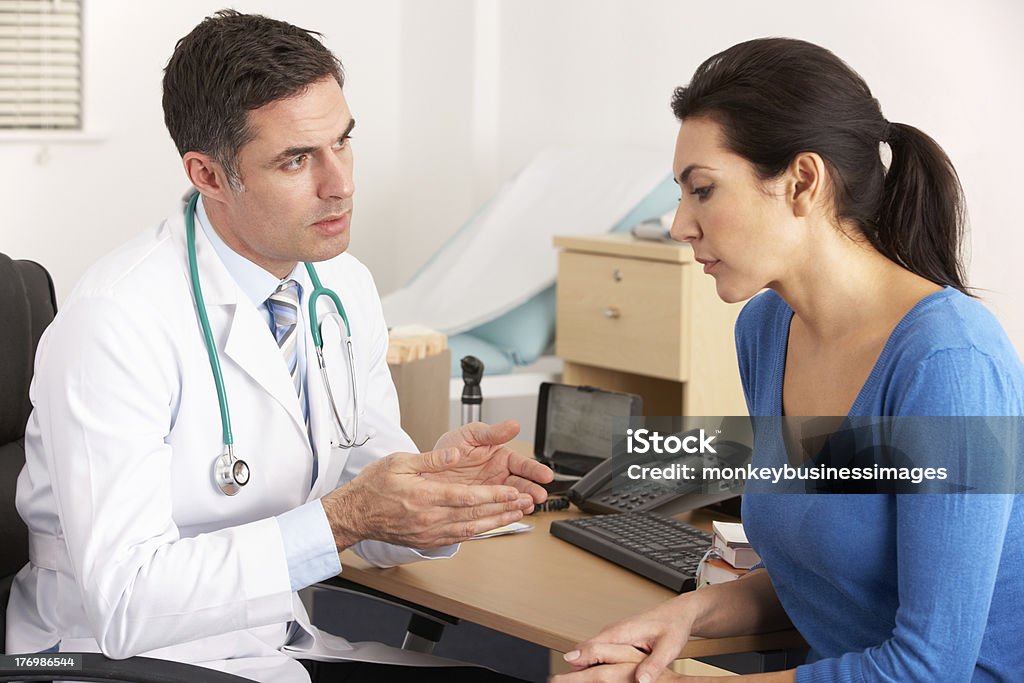 American doctor talking to woman in surgery American male doctor talking to depressed woman in surgery Talking Stock Photo