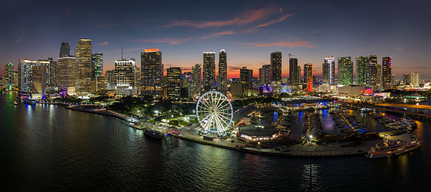 American urban landscape at night. Miami marina and Skyviews Observation Wheel at Bayside Marketplace with reflections in Biscayne Bay water and skyscrapers of Brickell, city's financial center.