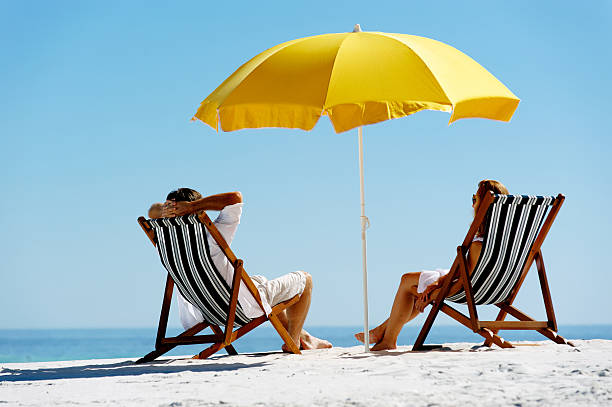 istock Couple enjoying summer beach time under yellow umbrella 176988352