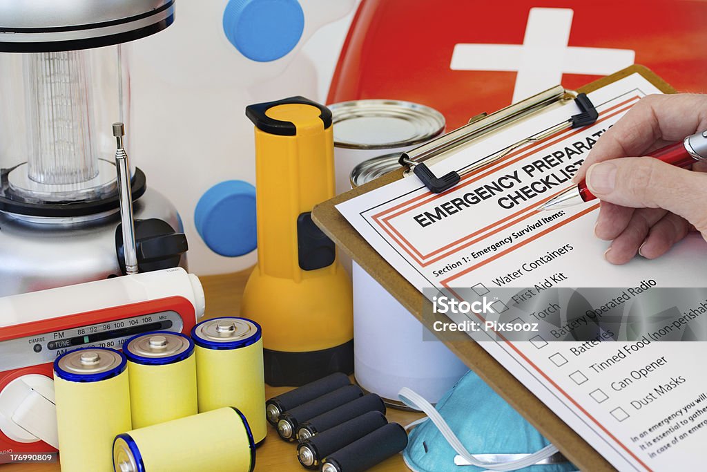 Hand completing Emergency Preparation List by Equipment Ready for disaster - checking off the items on the emergency  preparedness form Emergency Planning Stock Photo