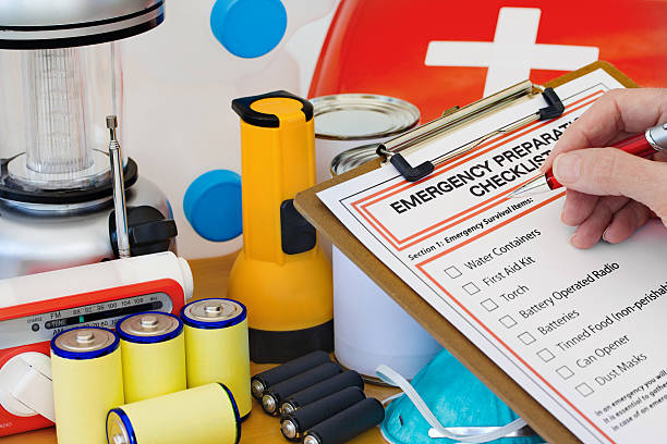 Hand completing Emergency Preparation List by Equipment Ready for disaster - checking off the items on the emergency  preparedness form natural disaster photos stock pictures, royalty-free photos & images