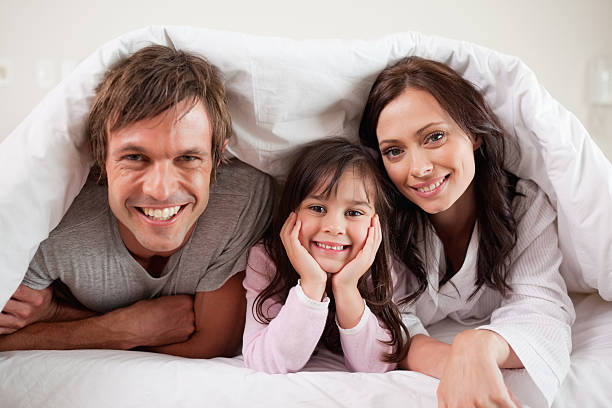istock Parents lying under a duvet with their daughter 176990891