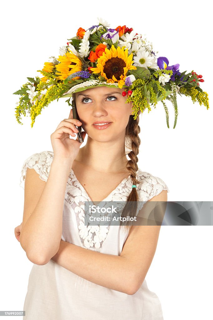 Beautiful girl with hat of flowers and phone Beautiful girl has on her head a hat of flowers and has in her hands a modern mobile phone. She communicates online. Adult Stock Photo