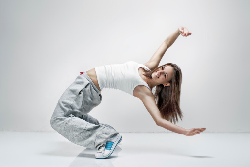 Young beautiful athletic girl dancing hip-hop in the studio.