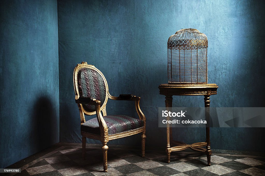 Louis table, armchair and old golden bird cage "Louis table, armchair and old golden bird cage in blue room with tiled floor" Birdcage Stock Photo