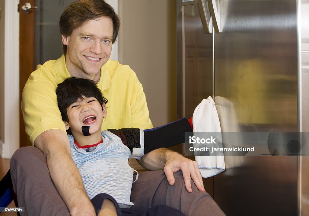 Padre in cucina con figlio disabile piano, Pulire il frigorifero - Foto stock royalty-free di Accudire