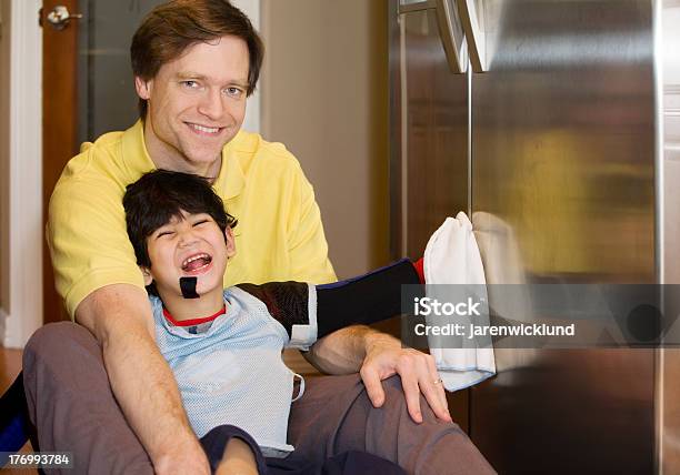 Foto de Pais Na Cozinha Com O Filho Andar Com Deficiência Limpando A Geladeira e mais fotos de stock de Adulto