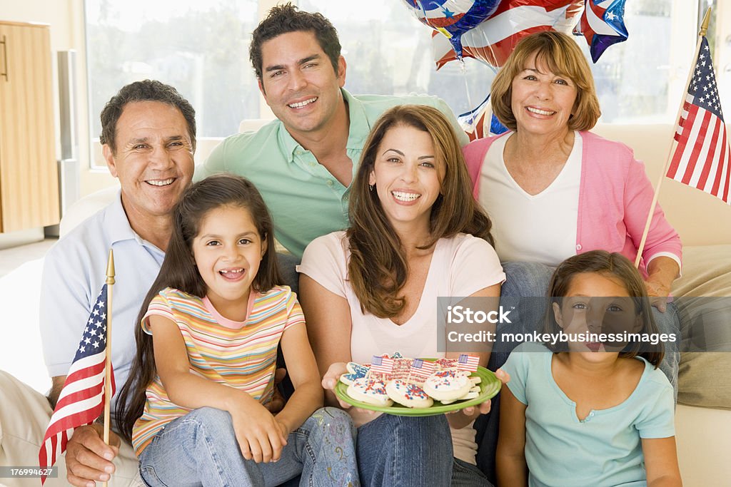 Famiglia in soggiorno sorridente sul quarto di Luglio - Foto stock royalty-free di Famiglia