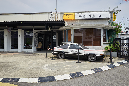IPOH , MALAYSIA - Sept 28,2023 : A black and white TOYOTA AE86 sports car is parked in The facade of Fujiwara Tofu restaurant