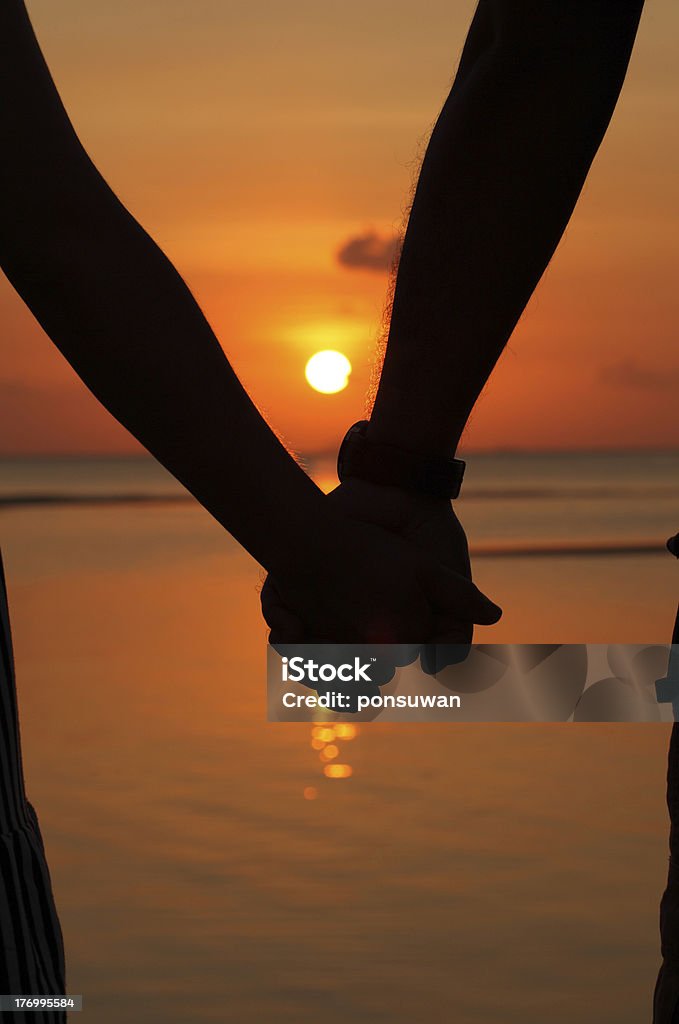 Silhouettes couples hands on sunset Holding Stock Photo