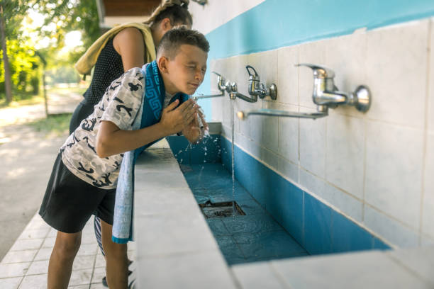 Kids having fun with water falling from a pipe from Lake Igapo. Pipe dripping water from Igapo Lake Dam.