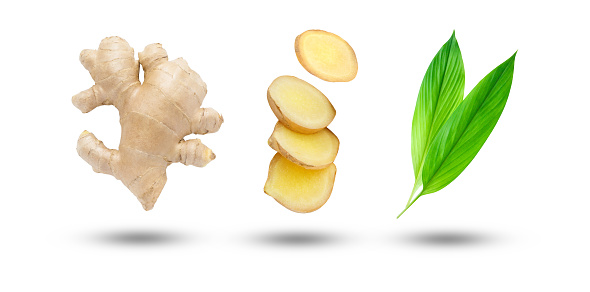 Flying ginger root with sliced and green leaves isolated on white background.