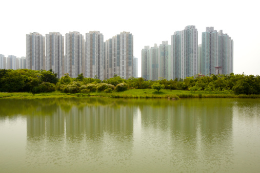 There are high-density residential apartments on a side of a lake.