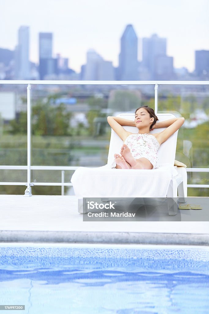 Mulher relaxante na piscina da cidade - Foto de stock de Cadeira recostável royalty-free