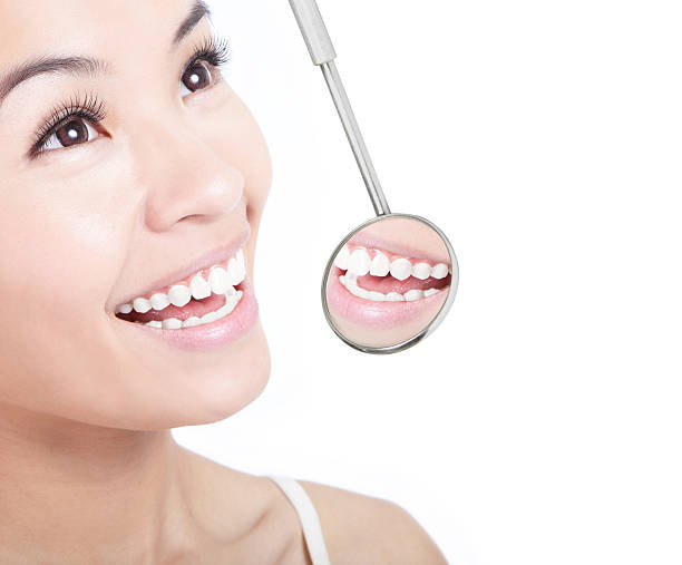 istock Smiling woman with a dentists mirror showing her teeth 176997237