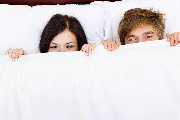 casal jovem feliz na cama - men sensuality photography high angle view imagens e fotografias de stock