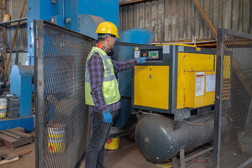 Metal Worker Control Industrial Air Compressor In A Factory