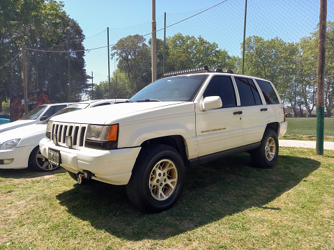 Remedios de Escalada, Argentina - Oct 8, 2023: old white 1990s Chrysler Jeep Grand Cherokee 4x4 SUV on the lawn at a classic car show in a park. Sunny day
