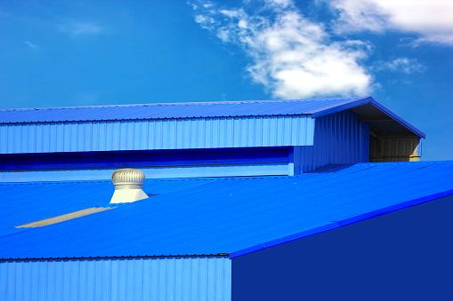 warehouse blue  metal sheet roof top against blue sky