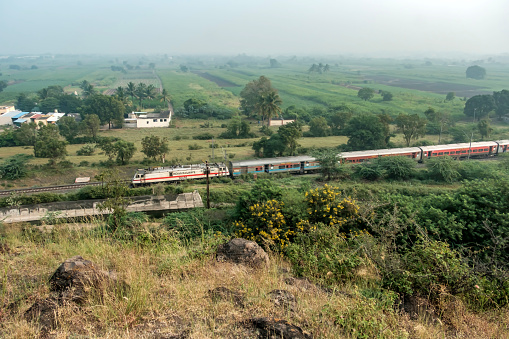 Sangameshwar, Maharashtra, India-February 26th, 2018:Indian Railways superfast double decker air-conditioned express train crossing a bridge in Konan.