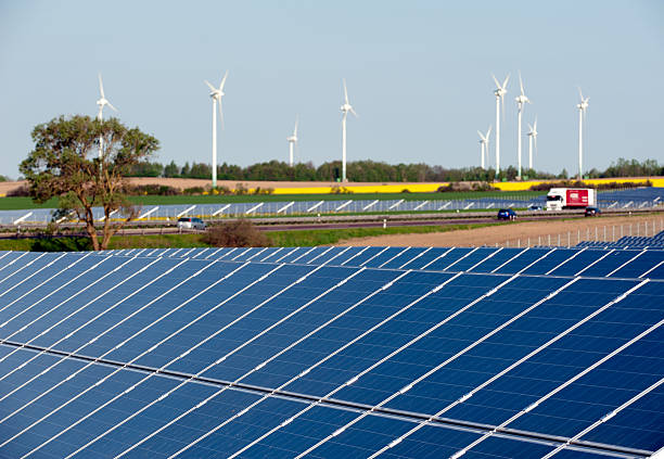 éoliennes et panneaux solaires dans le champ de colza - megawatt photos et images de collection