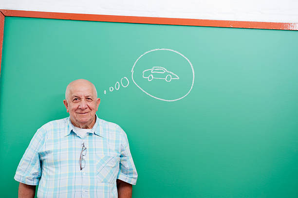 Senior man standing in front of blackboard stock photo