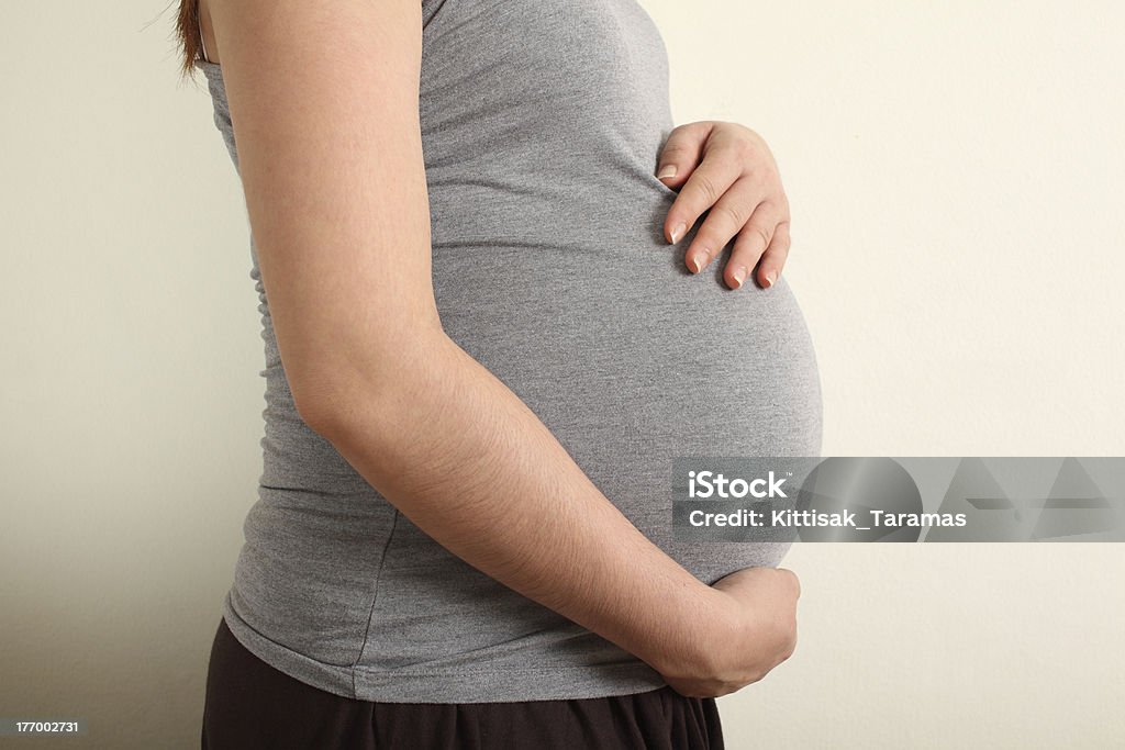 Pregnant asian woman caressing her belly. Warm tone color. Abdomen Stock Photo