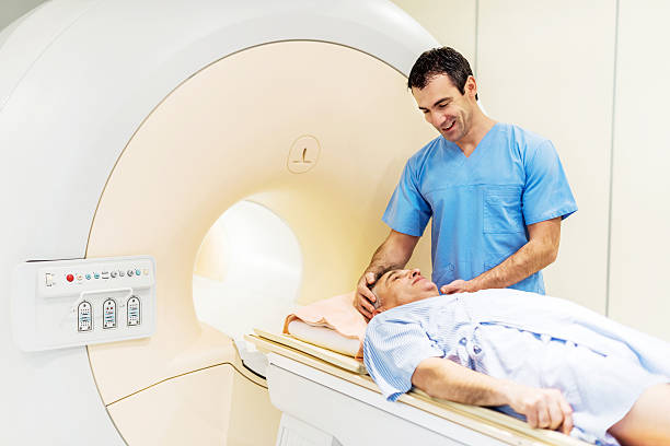 Preparation of the patient. Mid adult radiologist is preparing a patient who is about to take an MRI Scan.    pet scan photos stock pictures, royalty-free photos & images