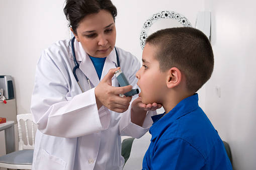 Female doctor applying oxygen treatment on asthma child. 