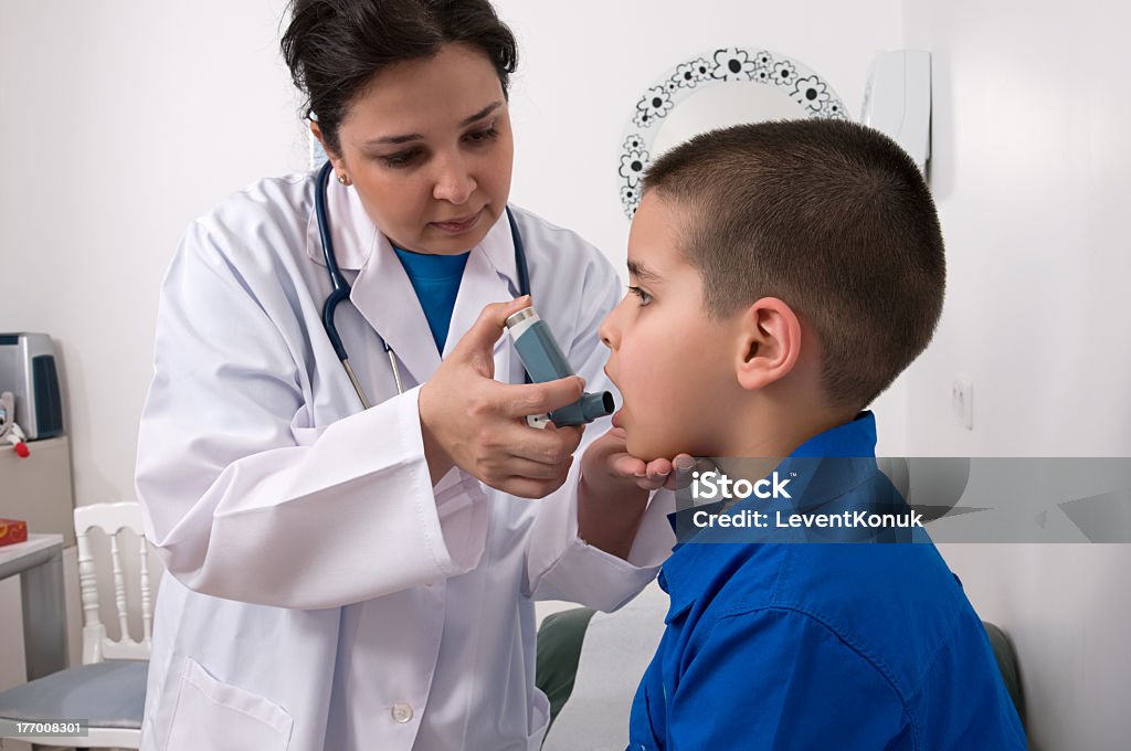 Doctor helping a boy with his asthma inhaler Female doctor applying oxygen treatment on asthma child.  Doctor Stock Photo