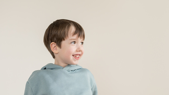 Portrait of a cheerful 6 year old boy on a beige background