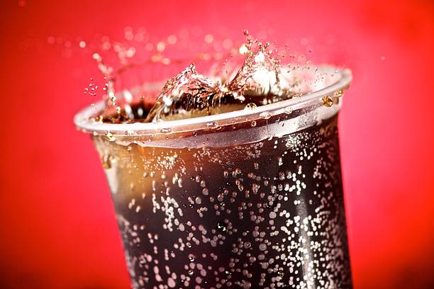 Cola splash on red background Cola splash on red background soda pop stock pictures, royalty-free photos & images