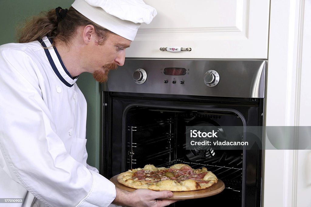 Giovane chef di preparazione pizza in cucina - Foto stock royalty-free di Abbigliamento