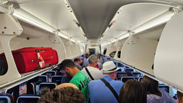 innenraum eines flugzeugs mit passagieren, die zu fuß stehen - economy class stock-fotos und bilder