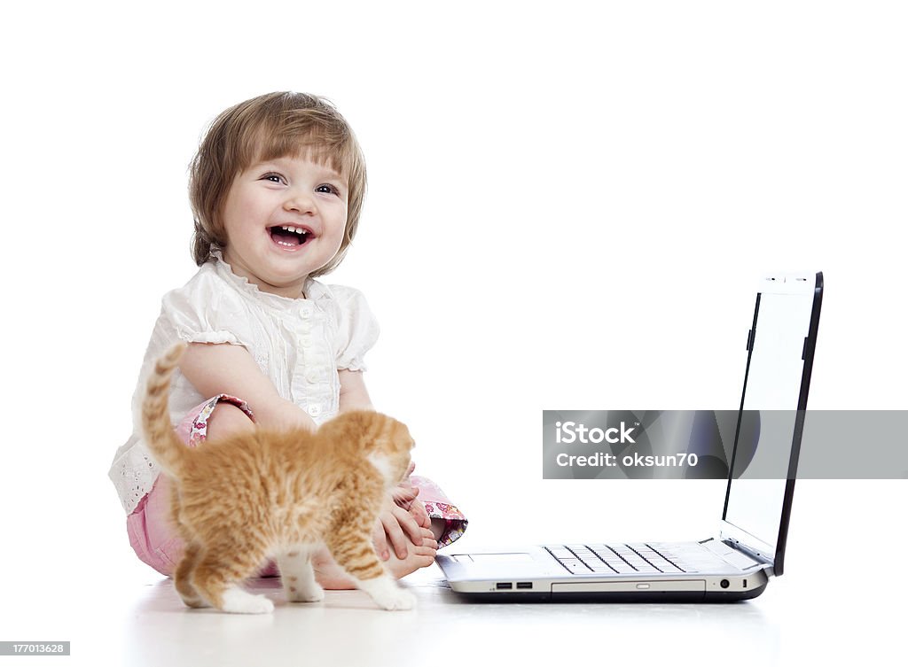 Engraçado garota usando um laptop. Salto Kitten pé perto da criança. - Foto de stock de 12-17 meses royalty-free