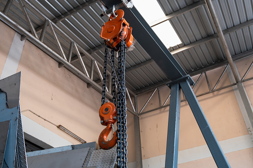 The construction crane in factory. chain hoist hanging on steel box