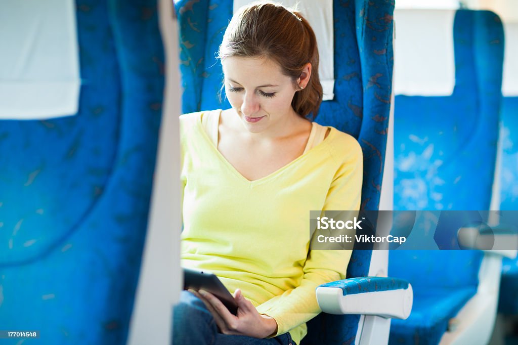 Giovane donna usando il suo computer tablet durante i viaggi in treno - Foto stock royalty-free di Adulto