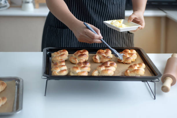 istock Female bakery chef or baker in black apron apply cheese on baked bread, culinary and bakery concept, homemade bakery small business 1770145791